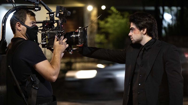 Operador de steadicam filma ator em cena noturna