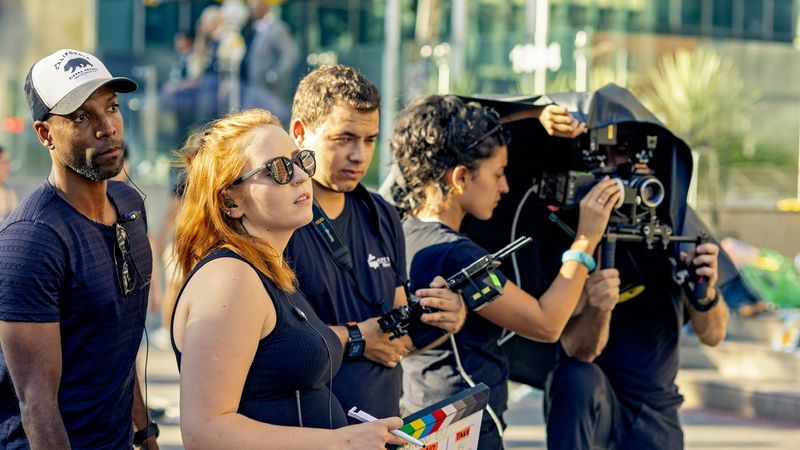 Equipe com claquete e câmera em gravação na rua
