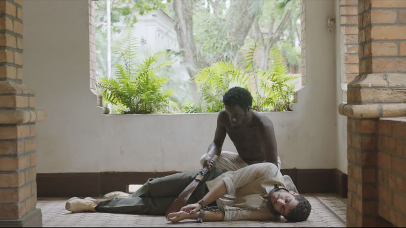 Frame de filme: dois homens em uma varanda de tijolos